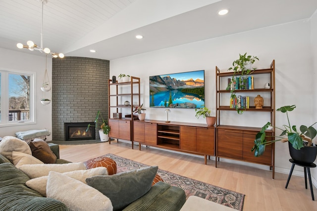 living room with vaulted ceiling, light wood-style flooring, recessed lighting, and a fireplace