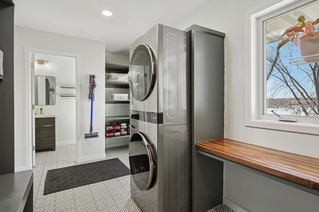 clothes washing area with laundry area, recessed lighting, stacked washer / drying machine, and baseboards