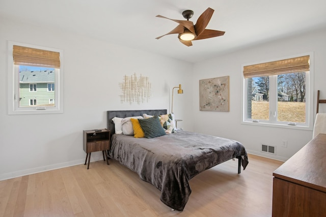 bedroom featuring visible vents, baseboards, a ceiling fan, and light wood finished floors