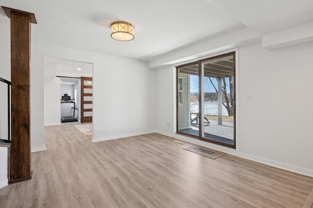 unfurnished room with light wood-style flooring and baseboards