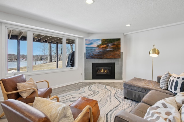 living area featuring wood finished floors, baseboards, a fireplace, recessed lighting, and a textured ceiling