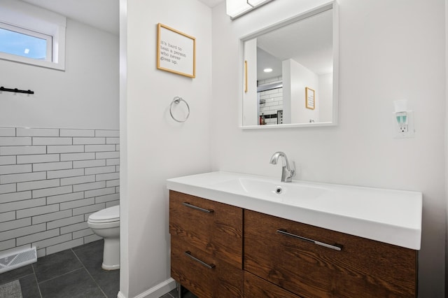 bathroom with tile patterned floors, visible vents, toilet, tile walls, and vanity