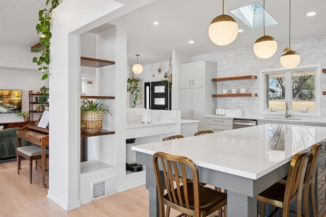 kitchen with visible vents, a sink, stainless steel dishwasher, a skylight, and light countertops