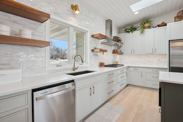 kitchen with open shelves, appliances with stainless steel finishes, wall chimney exhaust hood, and a sink