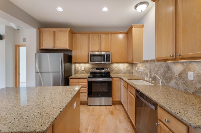 kitchen featuring stainless steel appliances, recessed lighting, tasteful backsplash, light wood-style floors, and a sink