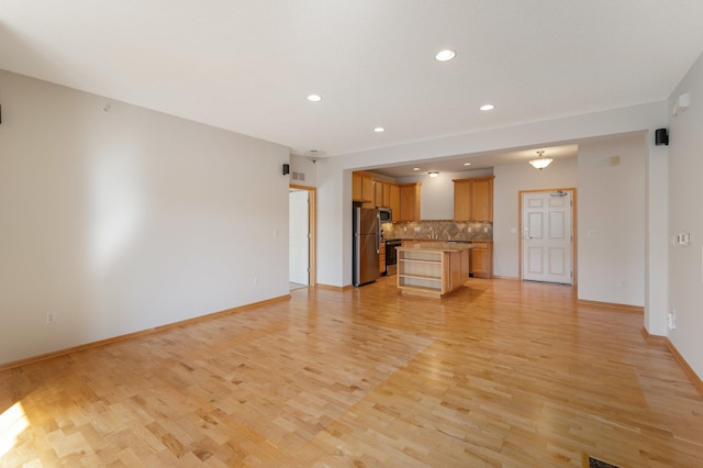 unfurnished living room featuring recessed lighting, light wood-style flooring, and baseboards