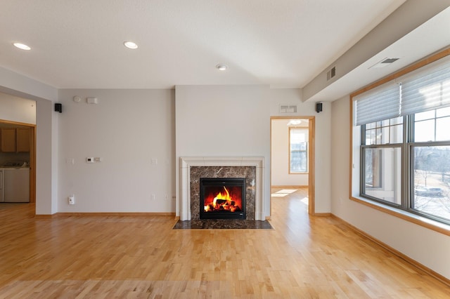 unfurnished living room with light wood-style floors, washing machine and dryer, a fireplace, and baseboards