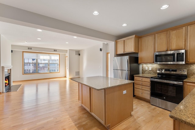 kitchen with tasteful backsplash, light wood-style flooring, open floor plan, a center island, and stainless steel appliances