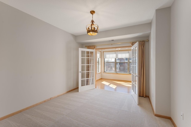 empty room featuring baseboards, light colored carpet, and french doors