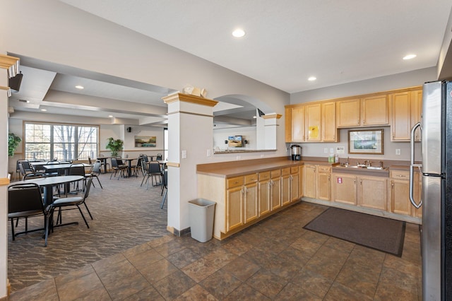 kitchen featuring recessed lighting, light brown cabinetry, freestanding refrigerator, open floor plan, and a sink