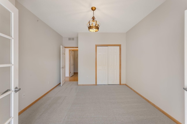 unfurnished bedroom featuring light carpet, visible vents, baseboards, and a closet