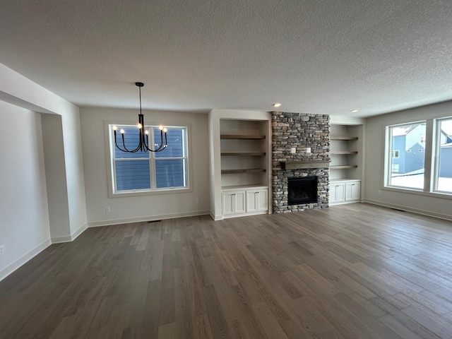 unfurnished living room with a fireplace, dark wood finished floors, a textured ceiling, and baseboards