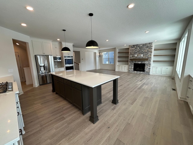 kitchen with pendant lighting, light countertops, appliances with stainless steel finishes, white cabinetry, and a kitchen island