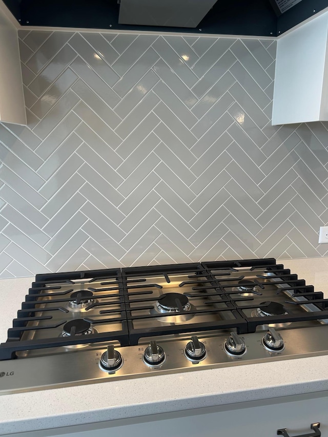 interior details featuring tasteful backsplash, stainless steel gas cooktop, and light countertops