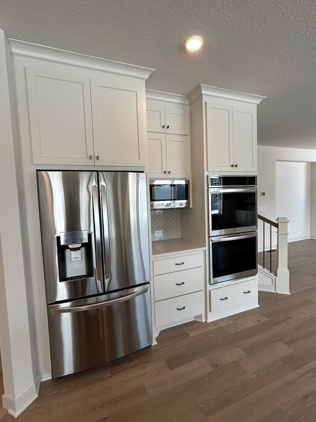 kitchen featuring white cabinets, stainless steel appliances, dark wood finished floors, and light countertops