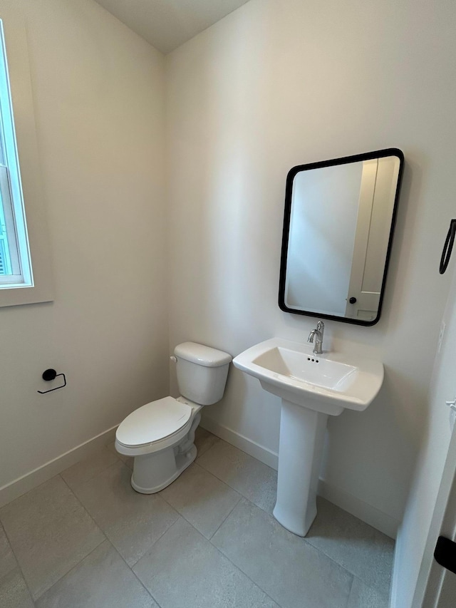 bathroom with baseboards, toilet, and tile patterned floors