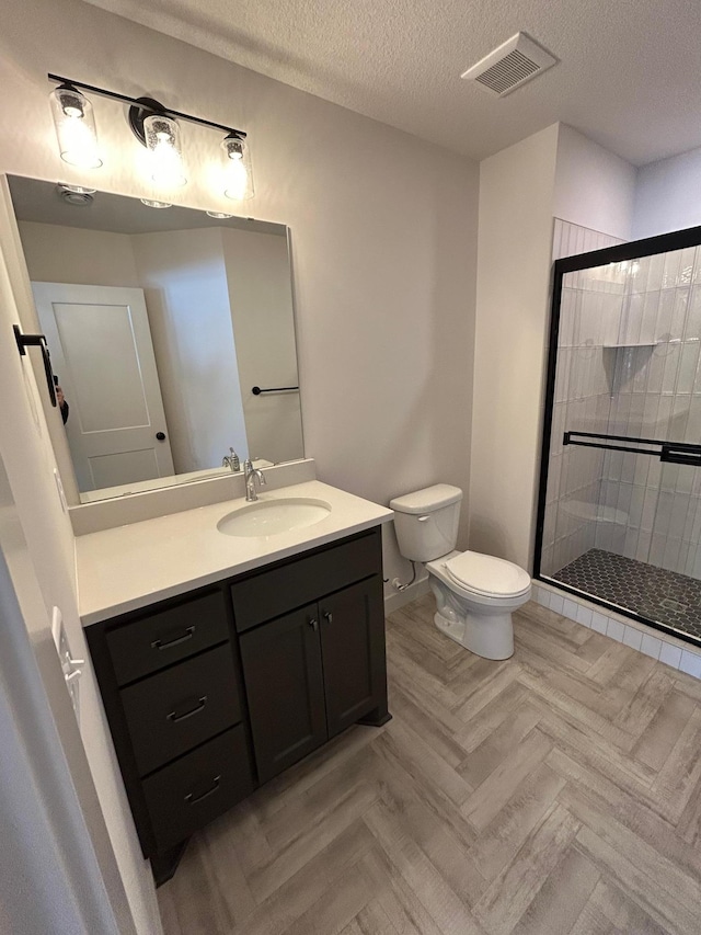 full bathroom featuring visible vents, a textured ceiling, a shower stall, and vanity