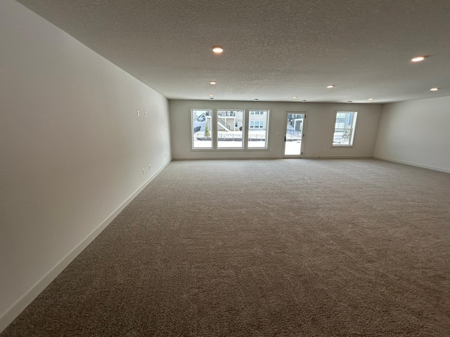 carpeted empty room featuring a textured ceiling, recessed lighting, and baseboards