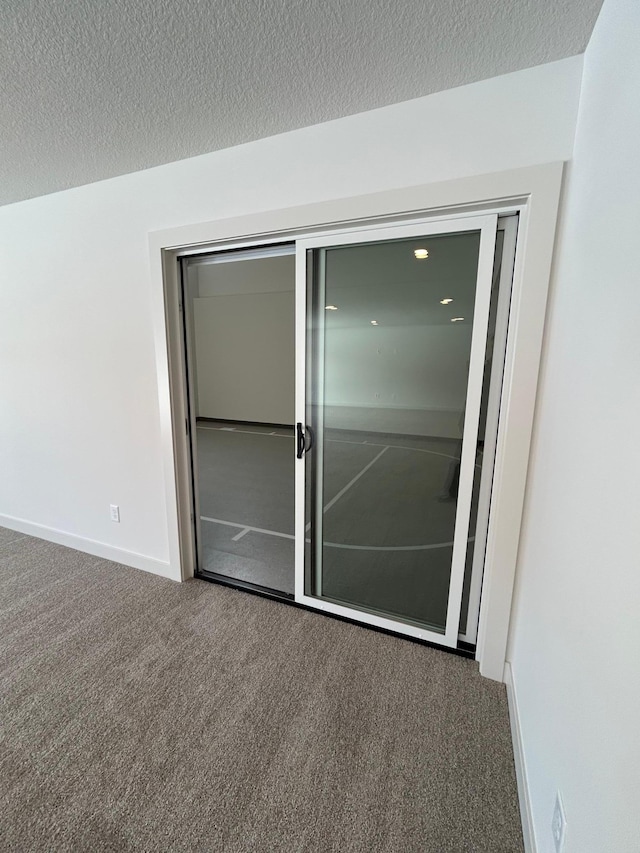 empty room with carpet floors, a textured ceiling, and baseboards