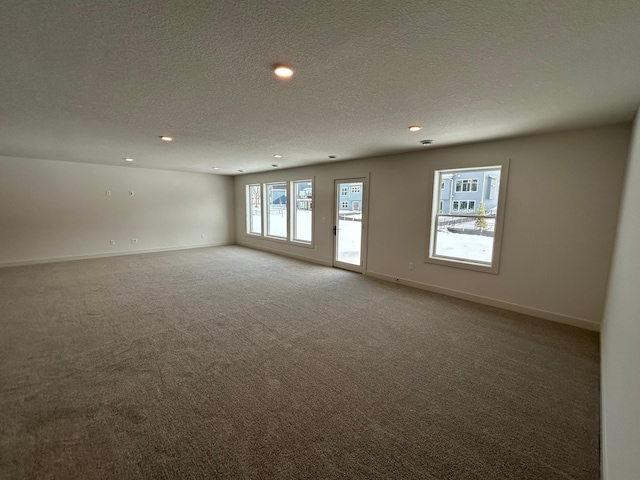 carpeted spare room featuring a textured ceiling, recessed lighting, and baseboards