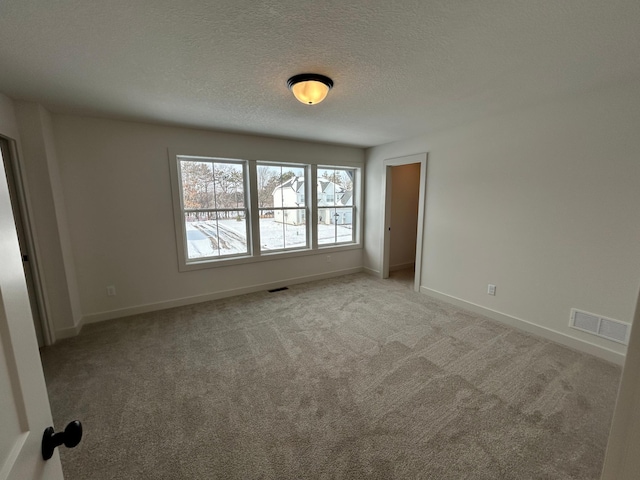 unfurnished bedroom with baseboards, visible vents, light carpet, and a textured ceiling