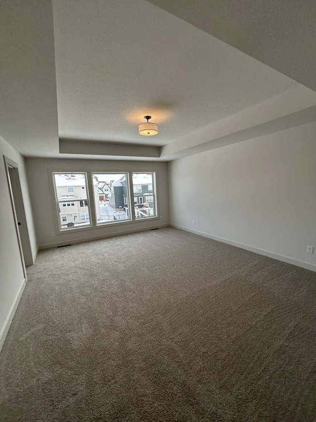 spare room featuring carpet flooring, a textured ceiling, and baseboards