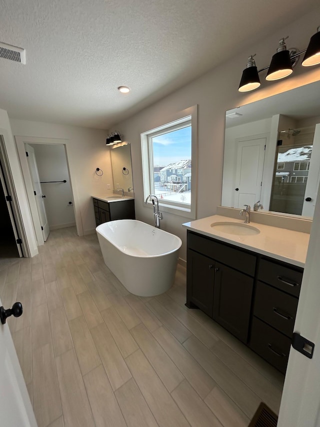 bathroom with two vanities, visible vents, a sink, and a shower stall