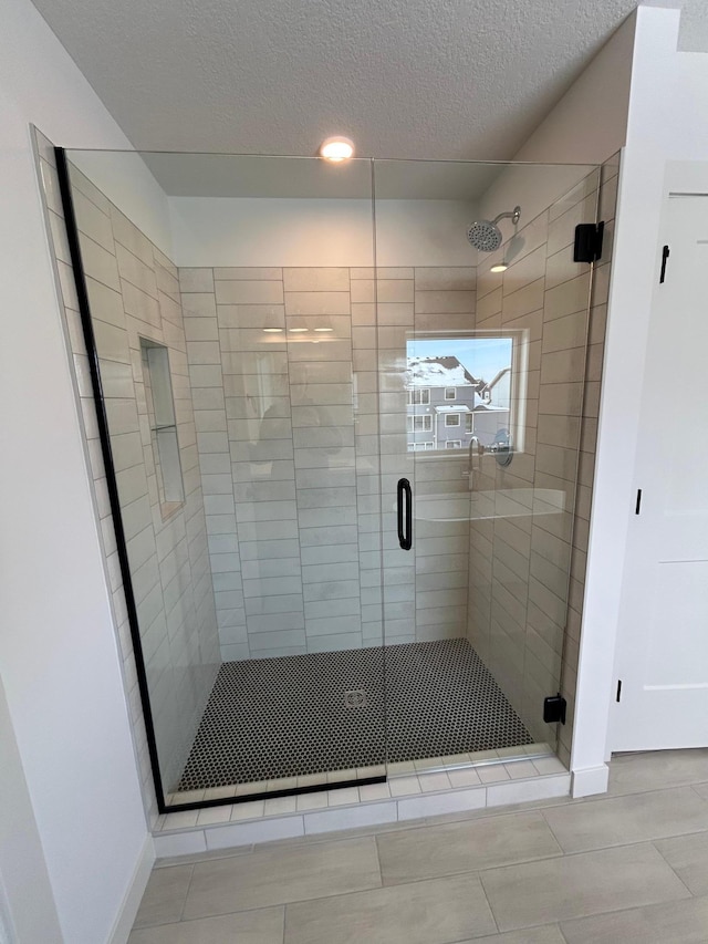 full bath featuring a shower stall and a textured ceiling