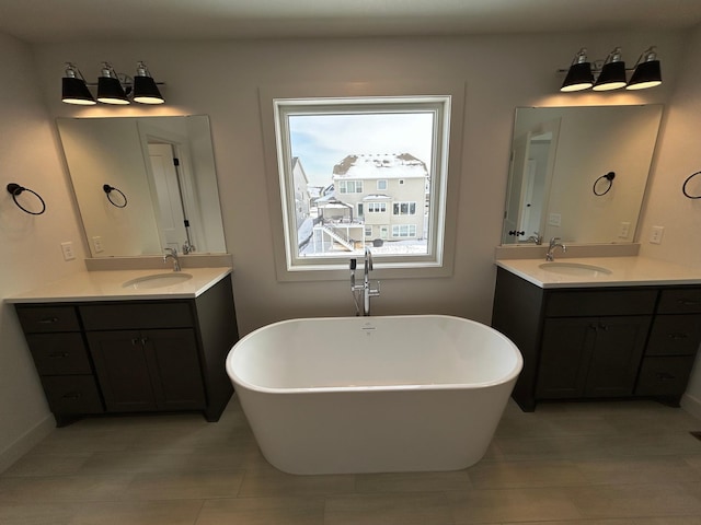 full bathroom featuring a soaking tub, two vanities, and a sink