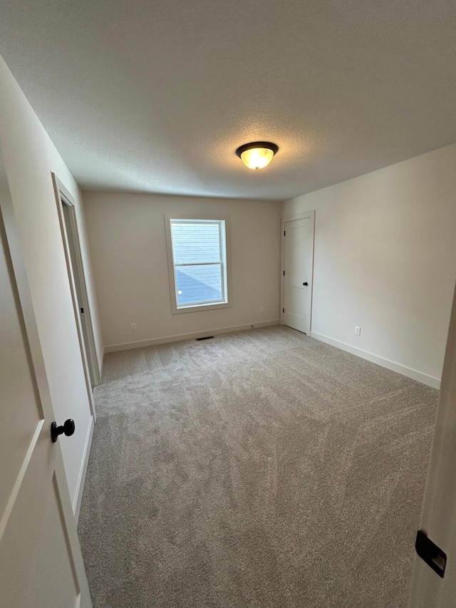 unfurnished bedroom featuring a textured ceiling, carpet flooring, and baseboards