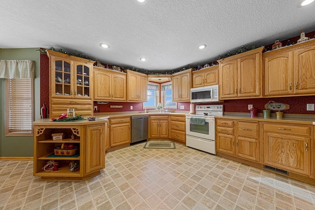 kitchen with appliances with stainless steel finishes, sink, and a textured ceiling