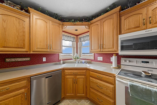 kitchen with sink, a textured ceiling, and white appliances