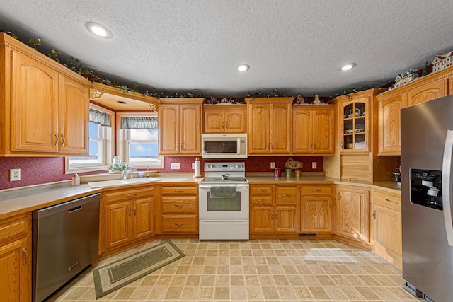 kitchen with appliances with stainless steel finishes, sink, and a textured ceiling