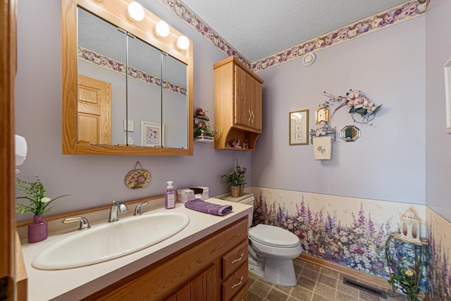 bathroom with vanity, toilet, and a textured ceiling