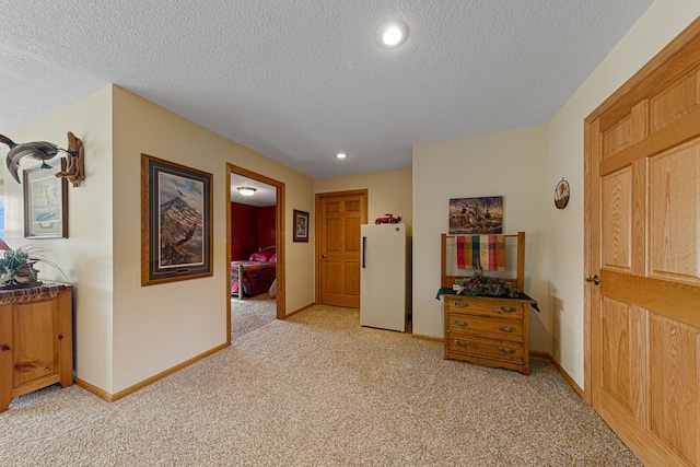 hallway with light carpet and a textured ceiling