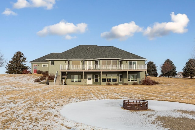 snow covered rear of property with a wooden deck and an outdoor fire pit