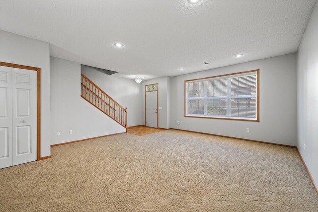 carpeted spare room with recessed lighting, stairway, baseboards, and a textured ceiling