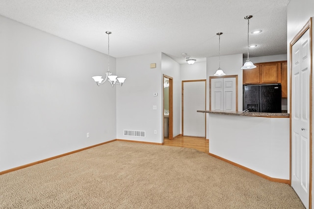 kitchen with light carpet, black fridge with ice dispenser, visible vents, brown cabinets, and decorative light fixtures