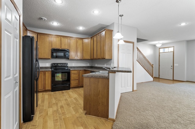 kitchen featuring dark countertops, black appliances, a peninsula, and brown cabinets