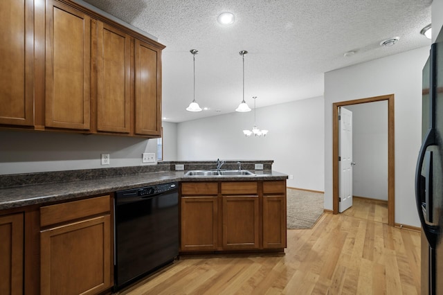 kitchen featuring dark countertops, brown cabinetry, a sink, a peninsula, and black appliances