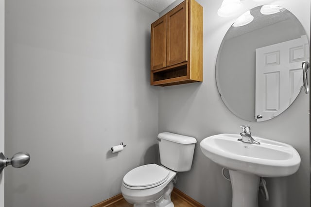 half bath featuring toilet and baseboards