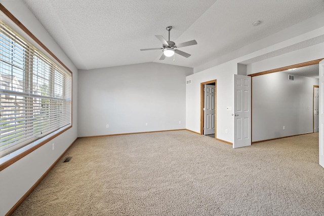 spare room featuring lofted ceiling, ceiling fan, a textured ceiling, baseboards, and carpet