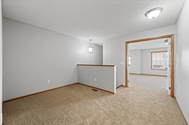 carpeted spare room featuring visible vents, a textured ceiling, and baseboards