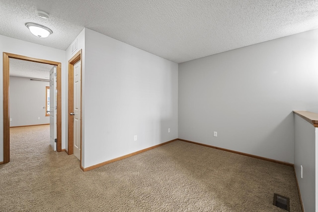 empty room with a textured ceiling, carpet floors, visible vents, and baseboards