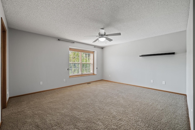 carpeted spare room featuring ceiling fan, a textured ceiling, and baseboards