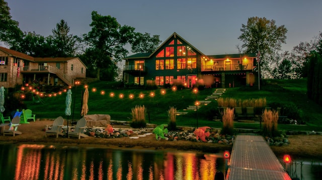 back of property featuring an outdoor fire pit and a deck with water view