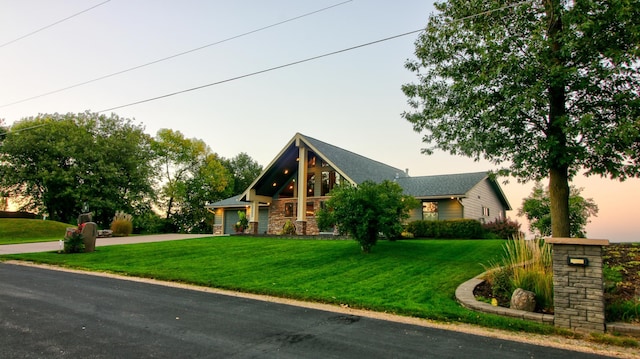 view of front of property with a yard, stone siding, driveway, and an attached garage