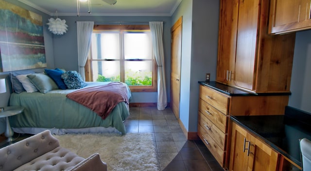 bedroom featuring dark tile patterned flooring, crown molding, and baseboards