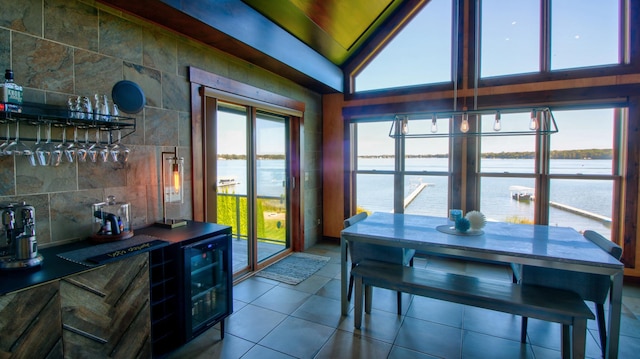 sunroom / solarium with bar, beverage cooler, a water view, and lofted ceiling