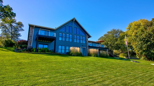 rear view of house featuring a lawn and stairs